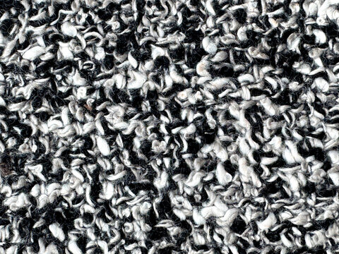 Close up texture of black and white boucle fabric. Curled and nubby knitted tufted texture. Suitable for sofa, upholstery, curtain, and drapery. Seamless background fabric texture.