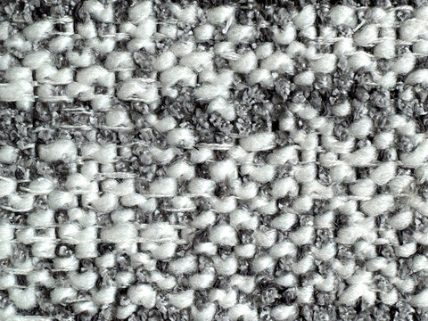 Close up texture of grey and white boucle fabric. Curled and nubby knitted tufted texture. Suitable for sofa, upholstery, curtain, and drapery. Seamless background fabric texture.