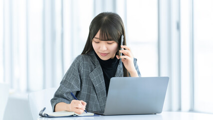 電話をしながらメモを取る女性ビジネスパーソン, Businesswoman taking notes while talking on phone © Trickster*
