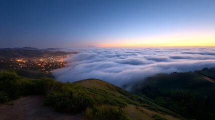 Fototapeta premium Dramatic fog blankets a coastal town at sunrise seen from a scenic hilltop vantage point