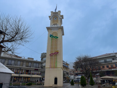 Xanthi clock tower with carnival light masks in central square.