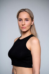 Portrait of a confident woman with long hair wearing a black sleeveless top against a neutral...