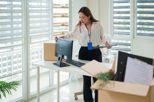 Adult Asian man professional packing items cardboard boxes office relocation new workspace setup happy employee business move organization planning corporate change