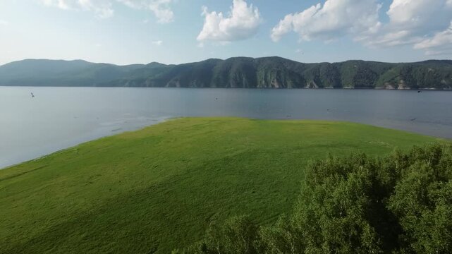 A lake in a national park in summer, birds flying over the water, filmed with a drone
