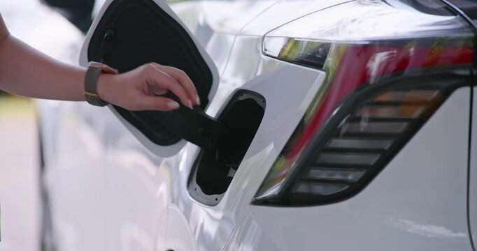 Close-up of a person charging a white electric vehicle using a CCS2 EV charging station. Clean energy transportation concept showcasing modern electric mobility and sustainable automotive technology.