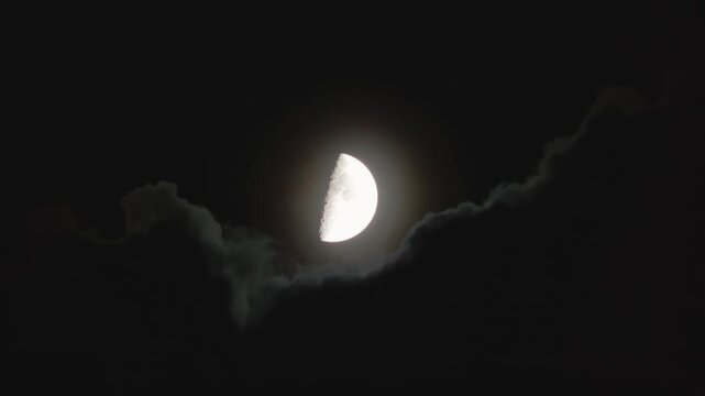 A dark cloud obscures the moon in the night sky. Changing weather and a spooky midnight