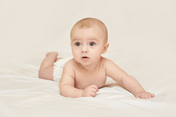 Caucasian Baby Lying On Soft White Blanket With Curious Expression.