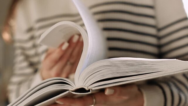 4K slow motion close up of woman turning pages of book at home. Cozy reading moment, education and self development concept, literature hobby indoors.