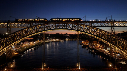 Fototapeta premium Sunset Luis I Bridge In Porto Portugal. Cars Driving Towards Downtown City On The Famous Bridge. Building Town Clouds Sky Illumination Urban. Town Outdoor. Porto Portugal.