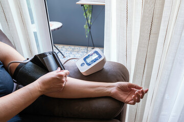 
Unrecognizable person measuring blood pressure with a digital monitor at home