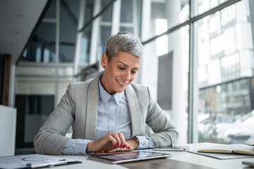 Mature businesswoman using digital tablet in modern office