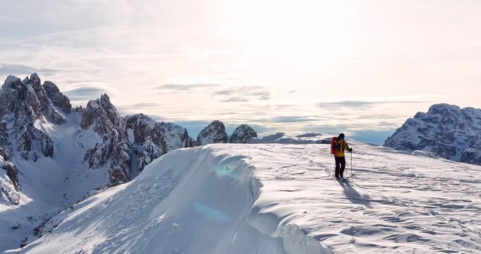 Aerial footage of a ski mountaineer in a snowy alpine ridge in Dolomites. Winter landscape, backcountry adventure, and solitude in breathtaking mountain scenery captured in 4K.