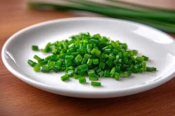 Fototapeta premium Finely diced chives on white plate, fresh green herb, culinary ingredient, kitchen table, healthy food, closeup view