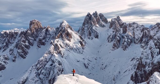 Aerial footage of a ski mountaineer in a snowy alpine ridge in Dolomites. Winter landscape, backcountry adventure, and solitude in breathtaking mountain scenery captured in 4K.