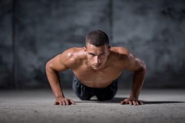 Obraz premium Young caucasian male athlete doing push-ups in gym setting