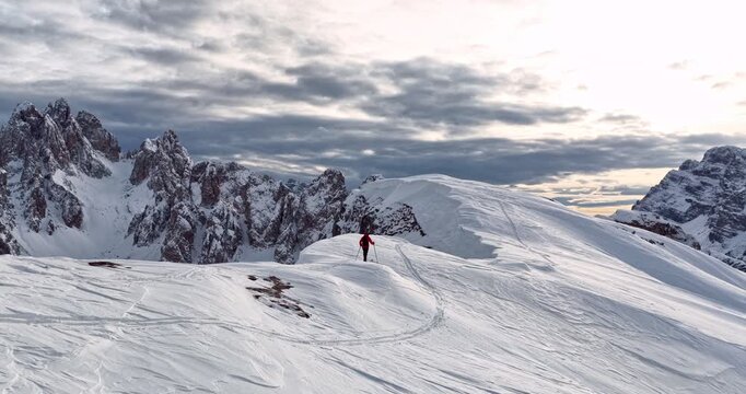 Aerial footage of a ski mountaineer in a snowy alpine ridge in Dolomites. Winter landscape, backcountry adventure, and solitude in breathtaking mountain scenery captured in 4K.