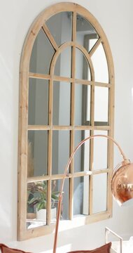 Vertical video: Camera panning up and right, revealing arched mirror and plant, copper lamp at home