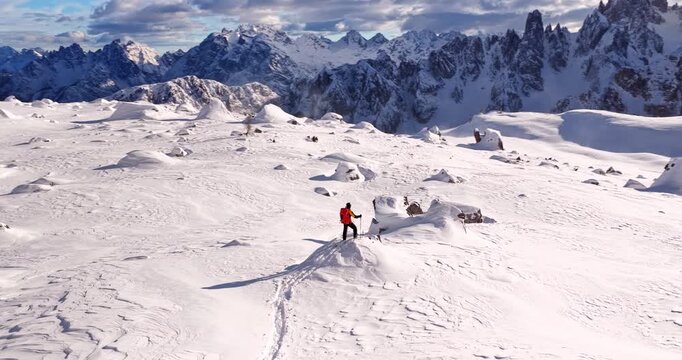 Aerial footage of a ski mountaineer in a snowy alpine ridge in Dolomites. Winter landscape, backcountry adventure, and solitude in breathtaking mountain scenery captured in 4K.