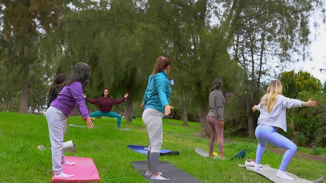 Group of multi generational women doing yoga exercise at city park - International female community, healthy lifestyle and multiracial people concept