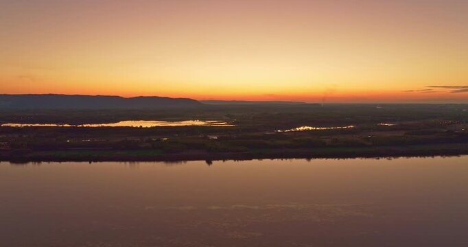 Elevated twilight view of Pak Kading town and bridge silhouetted against dramatic sunset colors, symbolizing calm countryside life in Laos.