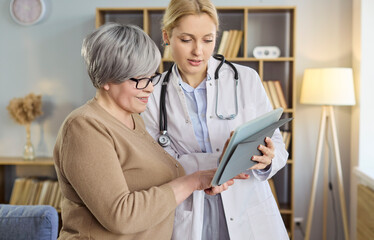Obraz premium Doctor with senior patient using tablet. At home during visit they review test results and explain next steps, delivering advice support and care. Clear concept of helpful home consultation.