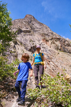 Smiling mother and son descending a mountain.