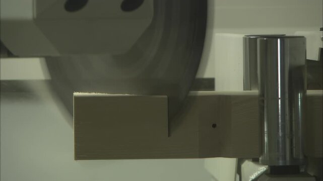 Close-up of spinning saw blade cutting timber beam