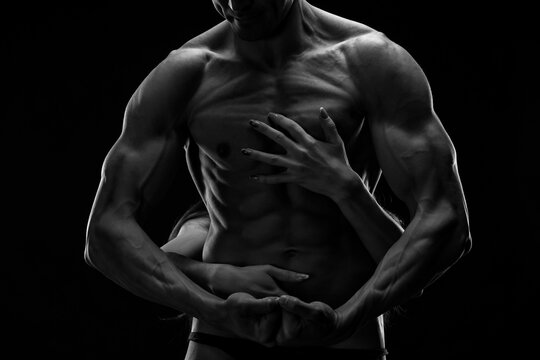 Artistic black and white studio portrait of athletic couple in acrobatic pose, concept of strength, trust and passion
