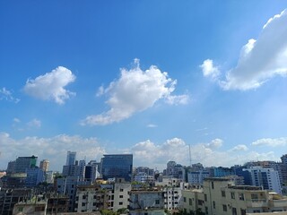 Fototapeta premium A cityscape with modern buildings and a blue sky with white clouds overhead