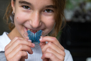 Child inserting blue orthodontic plate, step of pediatric teeth and bite correction, dental self-care.