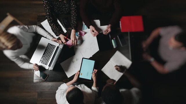 Timelapse of business team working together at office table from top view. Fast paced teamwork, productivity, collaboration and analysis with documents and digital devices indoors.