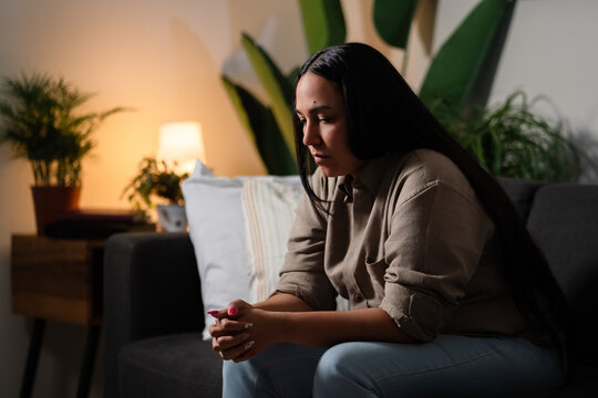 Woman experiencing sadness and worries alone in living room at night