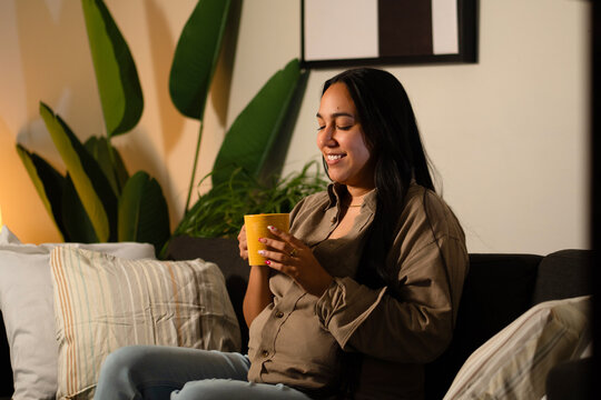 Satisfied woman enjoying warm drink at home