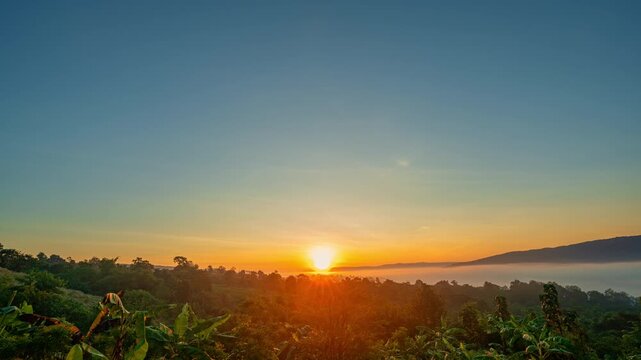 A cinematic drone aerial view of sunrise casting warm golden light over a misty mountain valley. Layers of fog drift between forested hills while distant peaks glow beneath a colorful dawn sky