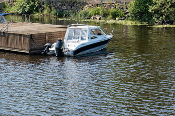 Boat docked by a wooden pier on a calm river during the afternoon sunshine