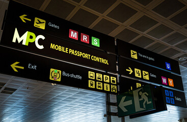 Airport terminal directional signage pointing passengers to Mobile Passport Control, gates, exit, busshuttle, taxi, metro and restrooms for efficient international travel navigation