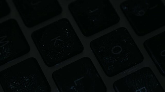 Close-up video of computer keyboard key illuminated by ultraviolet light revealing visible fingerprint on the surface. Concept of cyber security, digital privacy, forensic analysis, biometric 