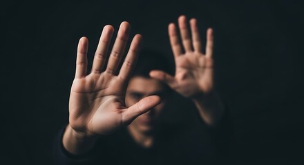 Two hands with palms facing forward against a dark background in a dramatic pose