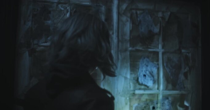 Lone woman with flashlight cautiously entering doors in scary, dark house - handheld medium shot