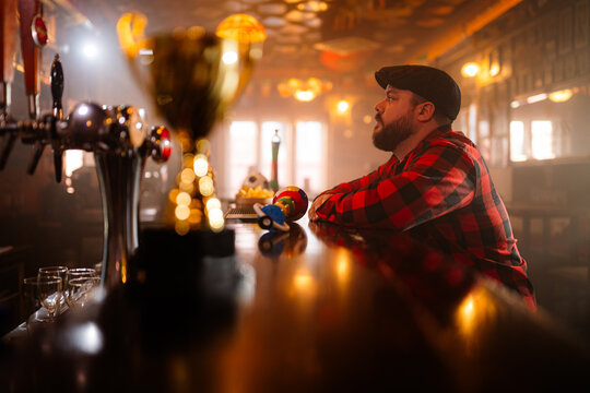 Man contemplating life at bar counter with trophy