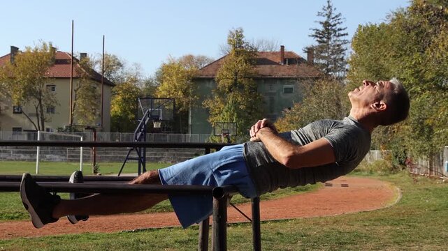 Strong Senior Male Doing Crunches on Parallel Bars - Calisthenics Park - Street Workout. Series Track Code: Fit-Mature-Man-54-Outdoor-Fitness-Series-2024  