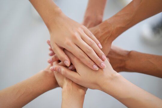 Multiple hands of different people stacked together in teamwork and unity