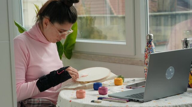 Individual focuses intently on detailed embroidery work at window