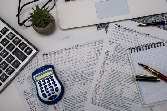 Tax accounting desk with calculator laptop and US 1040 income tax return documents
