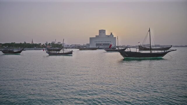 Doha, Qatar-February 2 2026: Museum of Islamic Art  exterior sunset shot showing dhows in the Arabic gulf with Qatar flag in foreground and Doha skyline in background