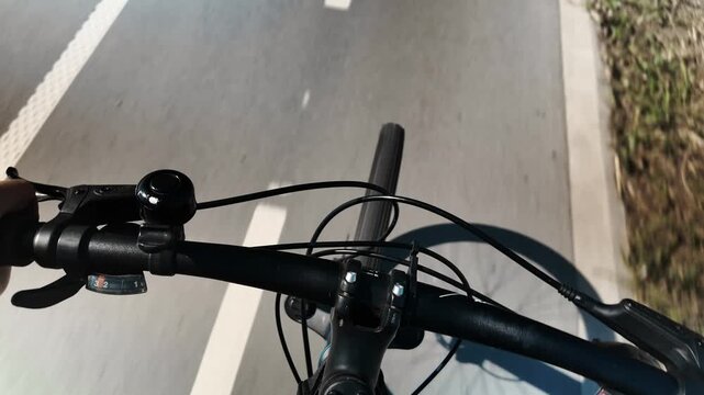 First person close up view of bicycle handlebars while riding on a smooth bike lane in summer. Dynamic motion and active cycling lifestyle concept