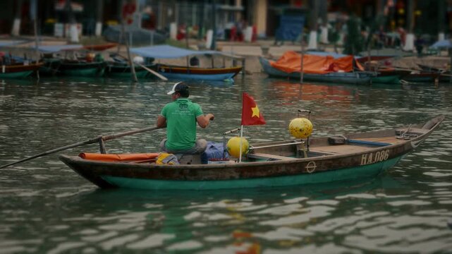 Man rowing small boat on river in harbor