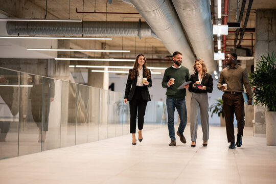 Business people walking in modern office corridor during coffee break