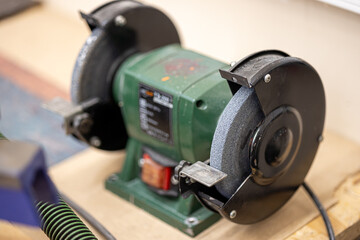 Bench grinder machine with abrasive stone wheel for sharpening tools in industrial workshop