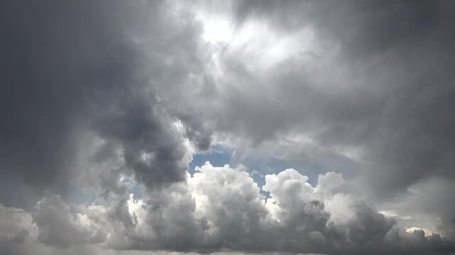 Time lapse storm clouds twist across dramatic sky with rapid shifting light and shadow. Accelerated cumulus masses churn in unstable atmosphere, showing chaotic weather change overhead.